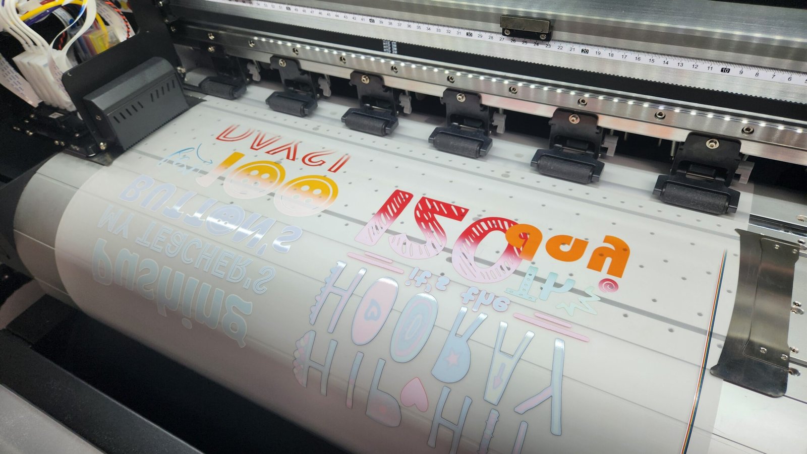 A printer producing colorful printed letters and designs on a roll of material.